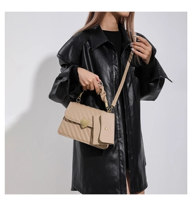 Detailed close-up of beige quilted crossbody bag with golden heart-shaped lock and pleated handle