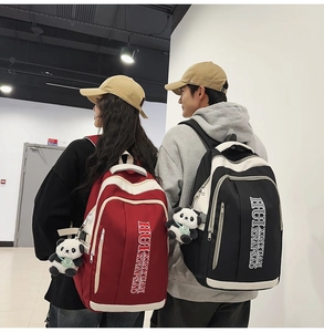 Detailed view of color-block nylon backpack with panda plush charm and brand lettering