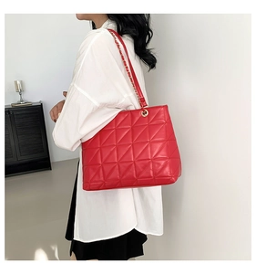 Détail du grand sac cabas matelassé rouge avec bandoulière chaîne porté par mannequin