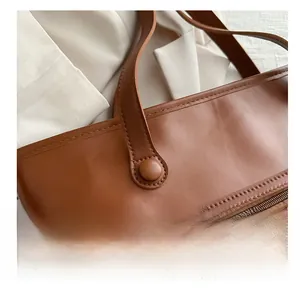 Dettaglio della borsa tote marrone con cuciture rinforzate e tasca con zip metallica