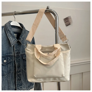 Detailansicht der cremefarbenen Canvas-Tasche mit verstellbarem Gurt und Fronttasche