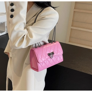 Detail of bright pink quilted chain bag with black metal hardware worn by a model