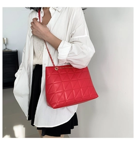 Détail du sac cabas matelassé rouge avec bandoulière chaîne porté par un mannequin en chemise