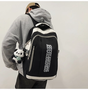 Detail of a large capacity black and white backpack with a cute panda pendant accessory