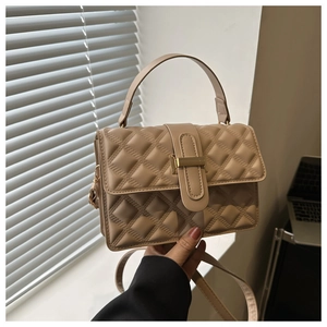 Close-up of beige quilted crossbody bag with rhombic pattern and gold metal buckle detail