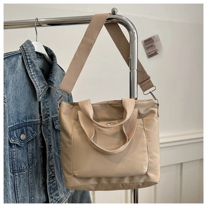Details der hellbeige Nylontasche mit Außentasche und silbernem Druckknopf aus Metall
