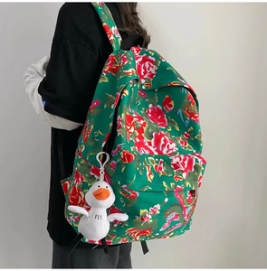 Detail view of the floral canvas backpack with a cute white duck plush toy charm