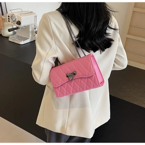 Detailed view of pink quilted chain bag worn by model in elegant white blazer suit