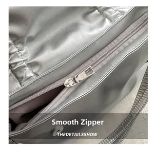 Detail view of the smooth metallic zipper and stitching on this silver tote bag