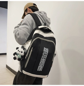 Side view of black nylon backpack with white contrast trim and panda plush accessory