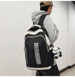 Male model wearing large contrast black and white nylon backpack with a panda keychain detail
