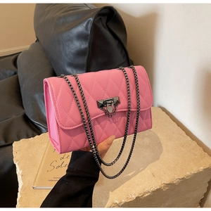 Close-up of pink quilted crossbody bag with dark grey chain strap and metallic lock detail