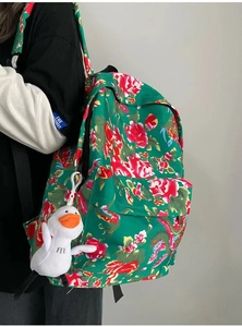 Detailed side view of green floral backpack with traditional peony pattern and duck charm