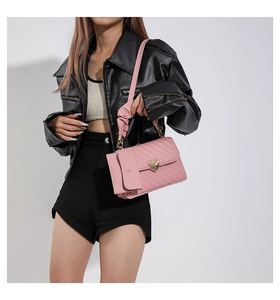 Pink quilted crossbody bag with gold heart clasp and cloud strap detail shown on model