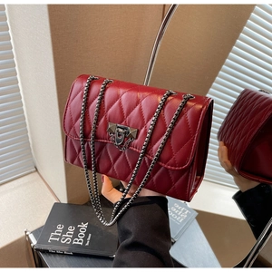 Close-up of wine red quilted crossbody bag with silver chain and metal clasp detail