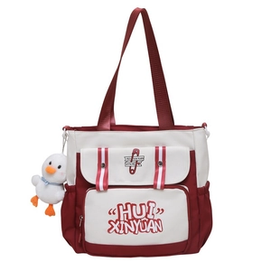 Detailed front view of fresh red and white canvas tote bag with cute duck charm accessory