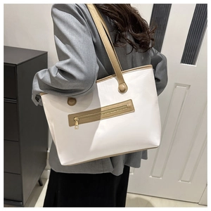 Dettaglio della grande borsa tote bianca con finiture in pelle marrone e zip dorata