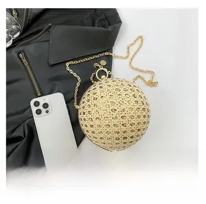 Detail of golden spherical evening clutch featuring hollow mesh design and gold chain strap