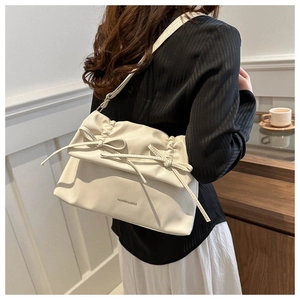 Close-up of cream soft leather tote bag featuring stylish bow tie and pleated details