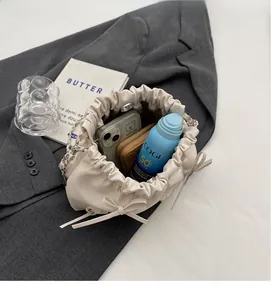 Espace intérieur du sac seau crème avec bandoulière chaîne sur un blazer gris