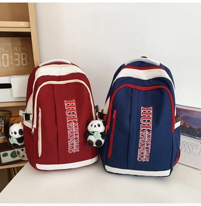 Detail of color-block nylon backpacks in red and blue with a cute panda pendant