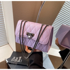 Close-up of light purple quilted shoulder bag with metal chain strap and twist lock detail