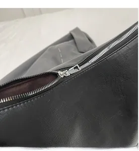 Détail d'une fermeture éclair en métal argenté sur un sac à bandoulière en cuir noir