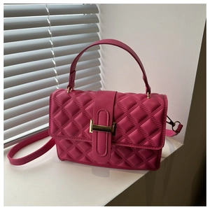 Detail view of rose pink quilted crossbody bag with gold metal clasp and top handle
