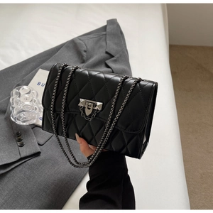 Close-up of black quilted leather shoulder bag with metal lock and chain strap detail