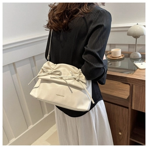 Detail of off-white leather tote bag with elegant bow tie and shoulder strap detail