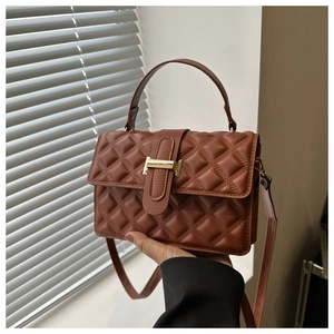 Close-up of brown quilted leather bag featuring elegant gold metal clasp and fine stitching