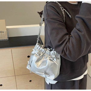 Détail du sac seau argenté à cordon avec nœuds décoratifs et bandoulière chaîne