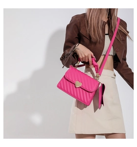 Detail of pink quilted handbag with heart lock and matching coin purse on shoulder strap