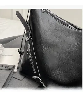 Gros plan sur un sac cabas noir en cuir avec fermetures éclair argentées et texture fine