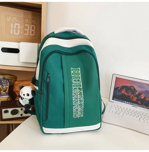 Detail view of a green nylon backpack with contrast white trim and a cute panda keychain