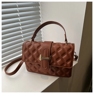 Macro detail of brown quilted texture and golden metallic clasp on casual crossbody handbag