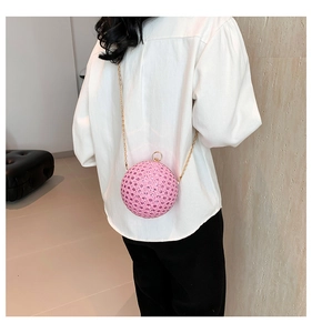 Rear view of a model wearing the pink rhinestone spherical evening bag with gold chain