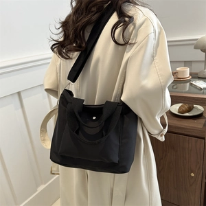 Minimalistische schwarze Nylon-Tragetasche für Damen, als stilvolle Umhängetasche an Model