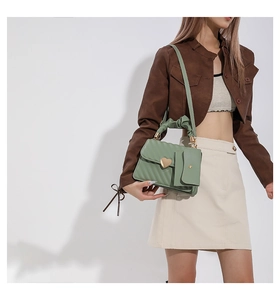 Detail of sage green quilted handbag with heart buckle and pleated handle with mini pouch