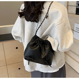 Vue détaillée du sac seau noir à cordon avec nœuds décoratifs et bandoulière chaîne