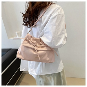 Close-up of light pink tote bag featuring a bow drawstring and gold fashion logo