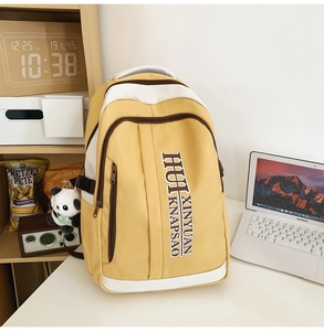 Detail of yellow nylon backpack with white contrast straps and cute panda plush keychain