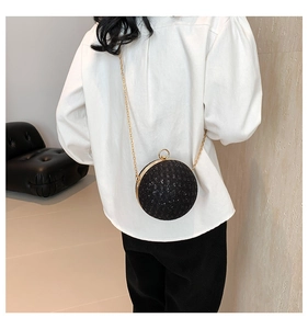 Model wearing a black spherical evening clutch with glitter sequins and gold chain strap