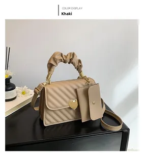 Detail of khaki PU leather handbag with diagonal stitching and golden heart metal clasp