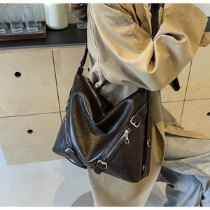 Détail d'un grand sac cabas marron foncé avec fermetures éclair et boucles métalliques