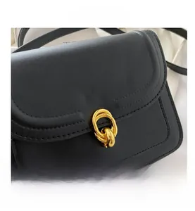 Close-up of black leather texture and elegant golden double-ring lock on minimalist flap bag