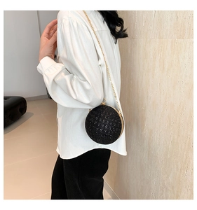 Close-up of black spherical evening clutch with sparkling sequins and gold metal chain