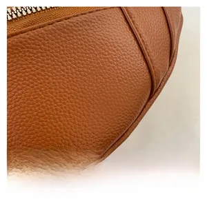 Gros plan sur la texture du cuir marron avec coutures précises et détails du zip métallique