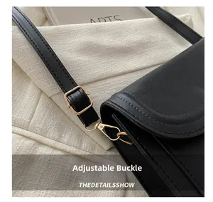 Detail of adjustable black leather strap with gold buckle and polished metal hook