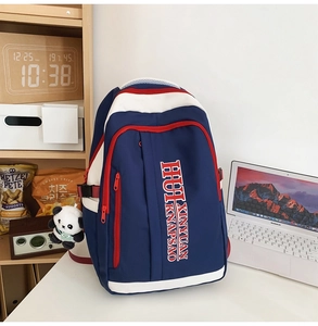 Detail showing tricolor nylon backpack with red contrast stitching and panda plush charm